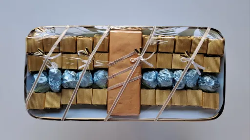 Rectangular box filled with rows of wrapped caramel and blue chocolates, tied with string.